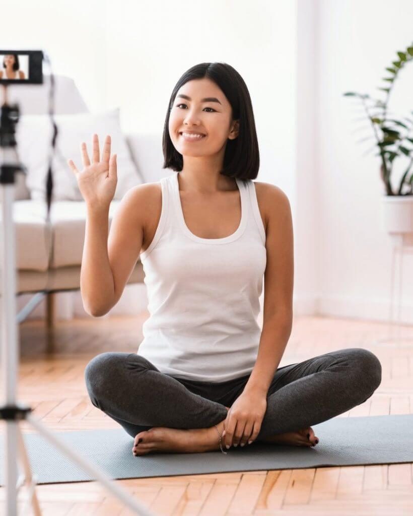sporty-asian-woman-waving-to-camera-home-training-concept